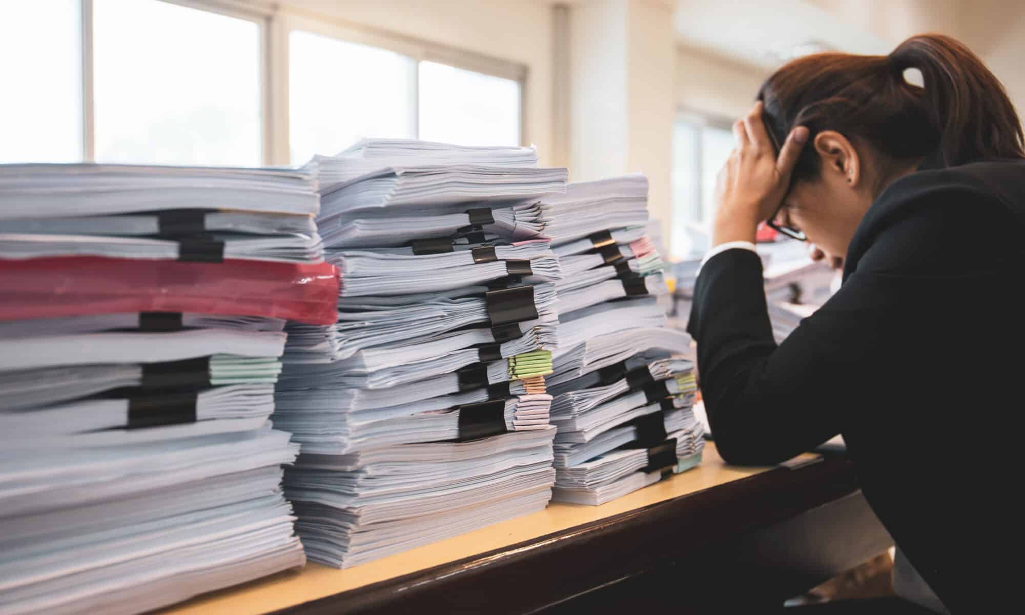 office worker distressed with lots of files and folders and legal paperwork