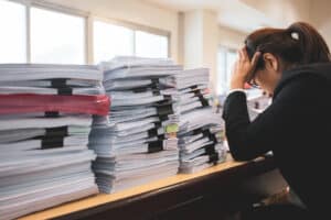 office worker distressed with lots of files and folders and legal paperwork